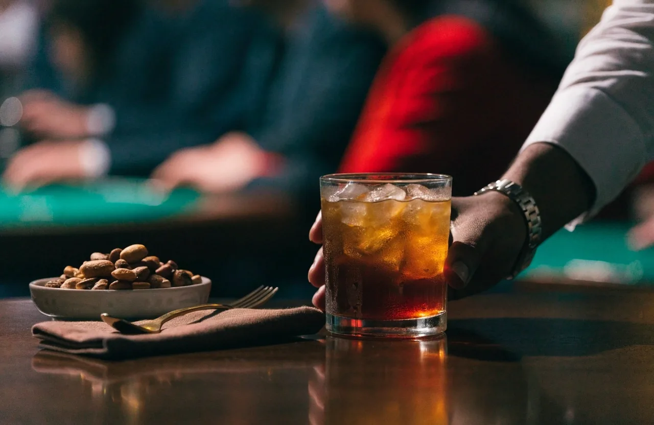 Pult lounge baru s nealko nápojem, ledovou kávou, mosaznou lžičkou a složeným plátnem ve teplém světle lampy